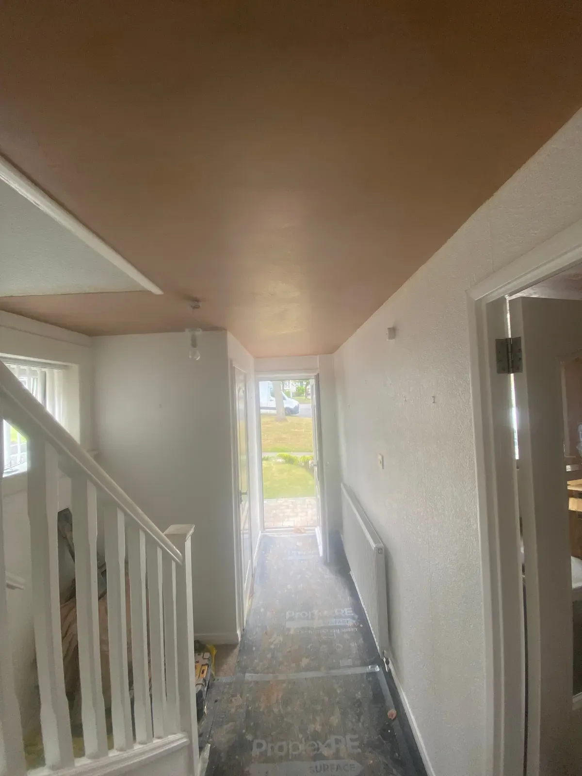 A hallway and stairs ceiling covered over the artex, with the floor fully protected