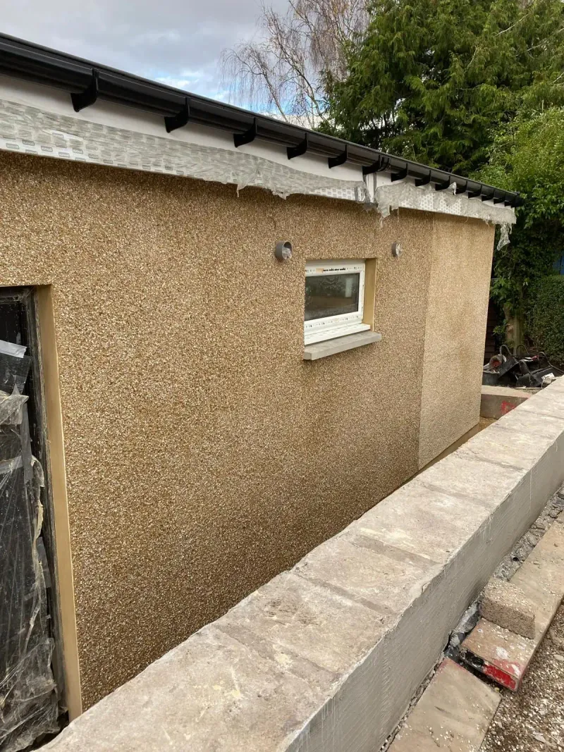 Finished harled wall on an extension, golden roughcast dash around a new window