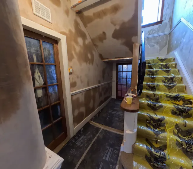 Stairwell walls replastered with protective sheeting down the stairs